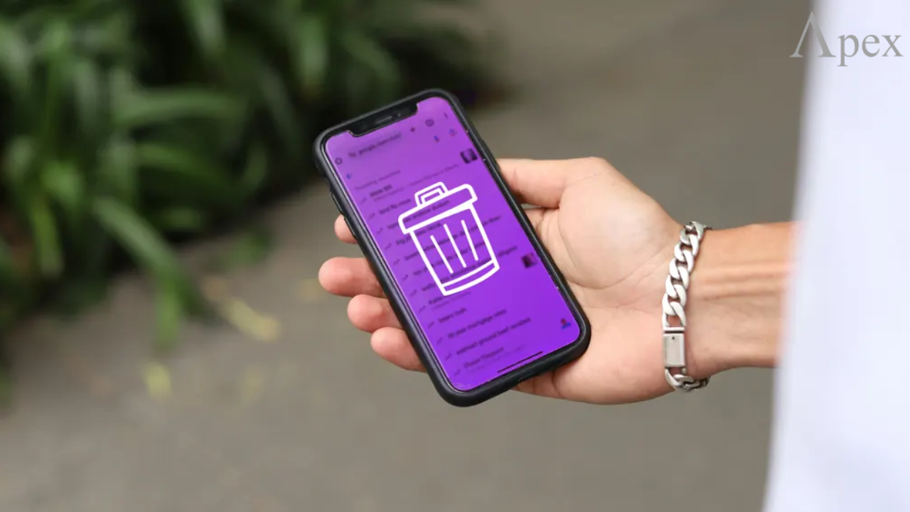 Deleting data or apps on a smartphone Person holding a smartphone with a trash bin icon on the screen, symbolizing deleting data or apps.