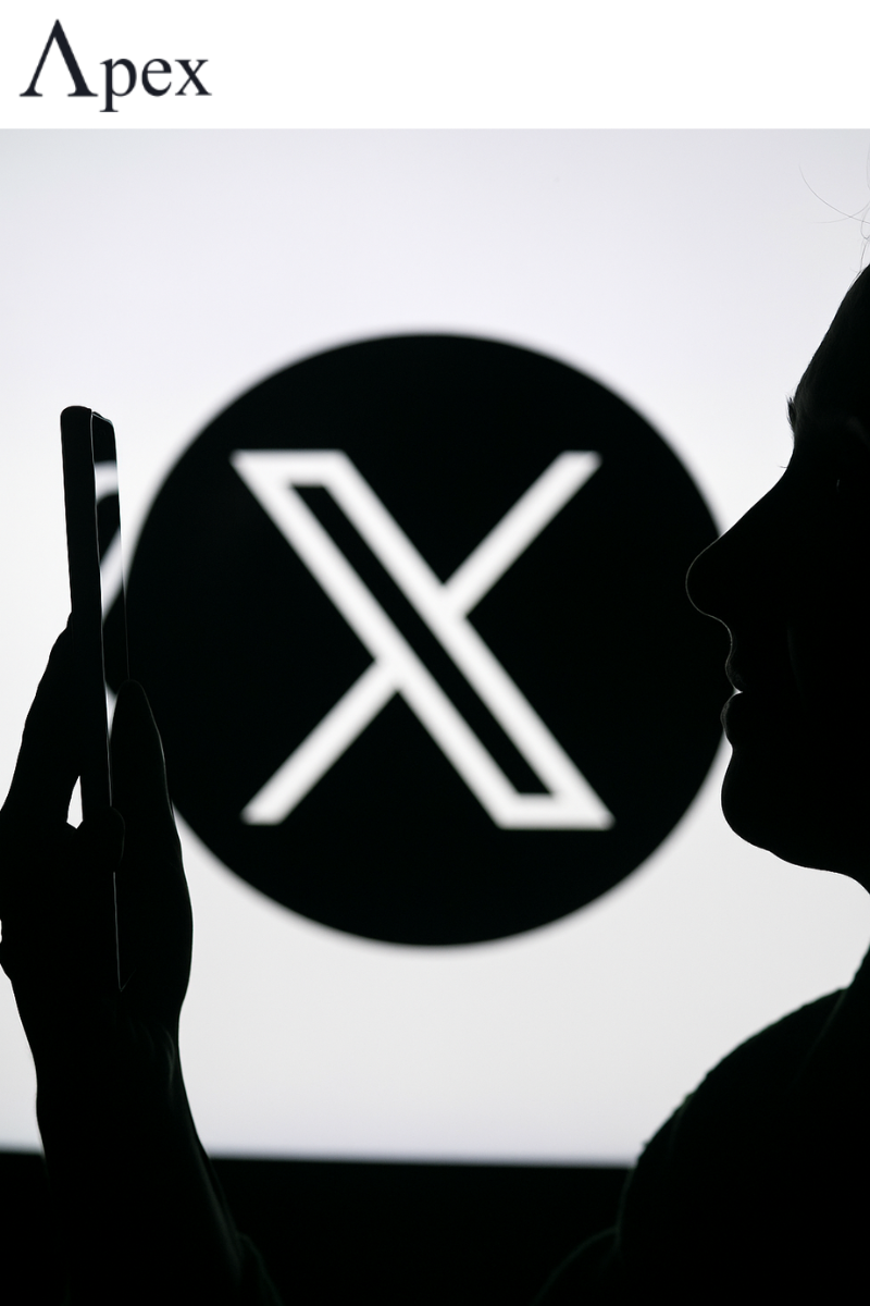 Silhouette of a person holding a smartphone in front of a large X logo background